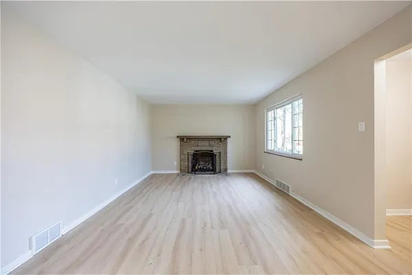 an empty room with wooden floor windows and fireplace