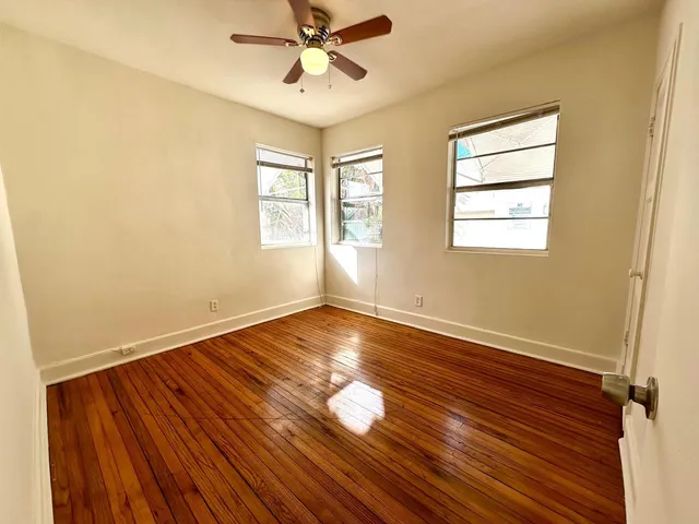 a view of an empty room with wooden floor and a window