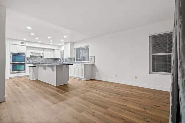 a open kitchen with a refrigerator and a wooden floor