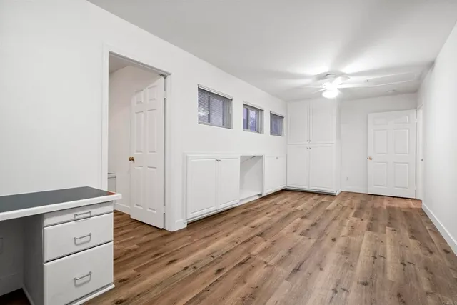 a view of empty room with wooden floor and fan