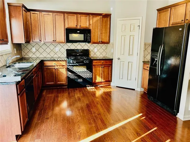 a kitchen with granite countertop a refrigerator a stove top oven a sink and dishwasher