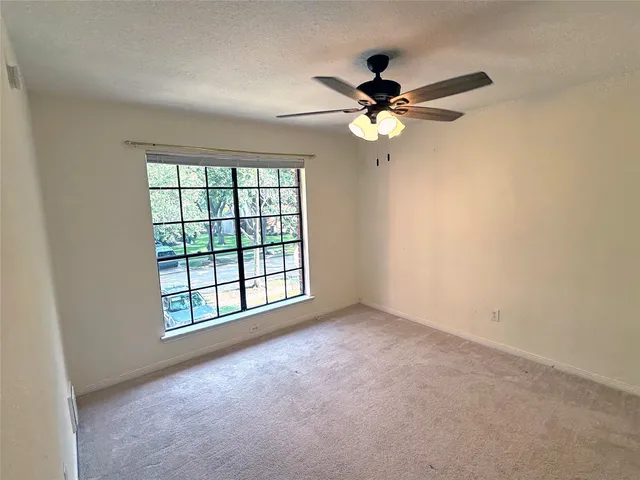 an empty room with windows and fan