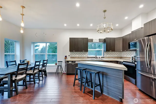 a kitchen with stainless steel appliances a table chairs refrigerator and microwave