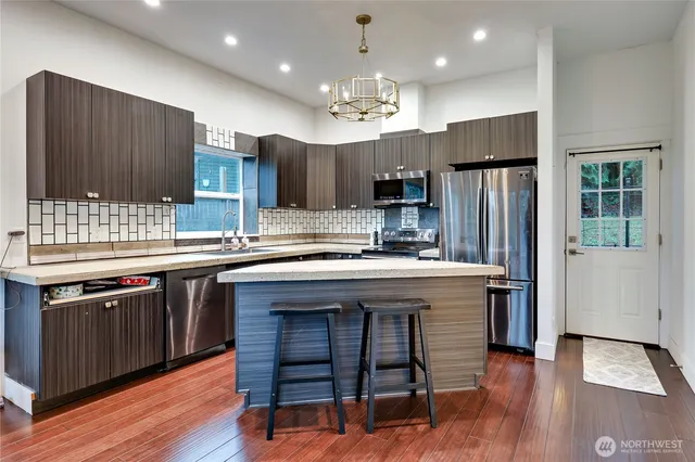 a kitchen with kitchen island granite countertop wooden cabinets and refrigerator