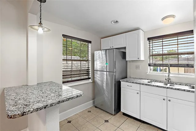 a kitchen with stainless steel appliances granite countertop a refrigerator a sink and white cabinets