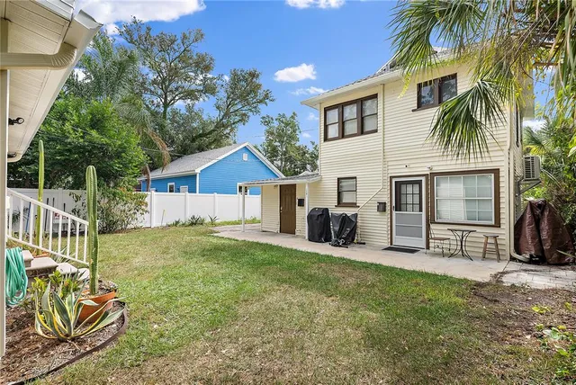a white house with a small yard and large tree
