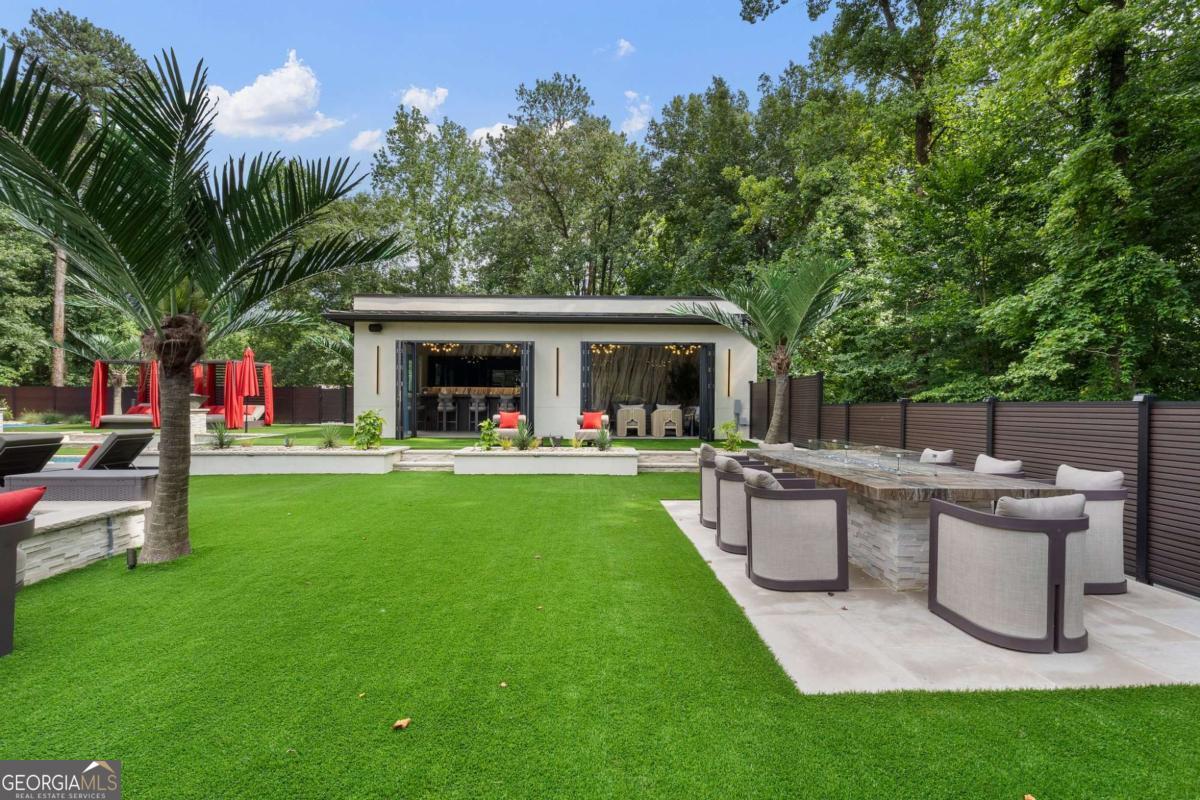 1386 Moores Mill Road Northwest Atlanta, GA 30327 - Photo 19 of 58 a view of a patio with table and chairs potted plants and large tree