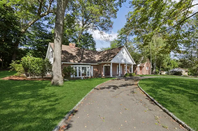 a view of house with a big yard and large trees