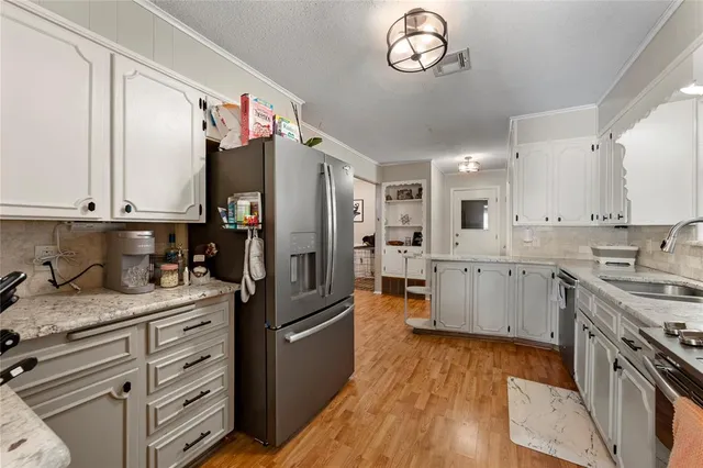 a kitchen with a sink dishwasher a refrigerator a stove and white cabinets with wooden floor