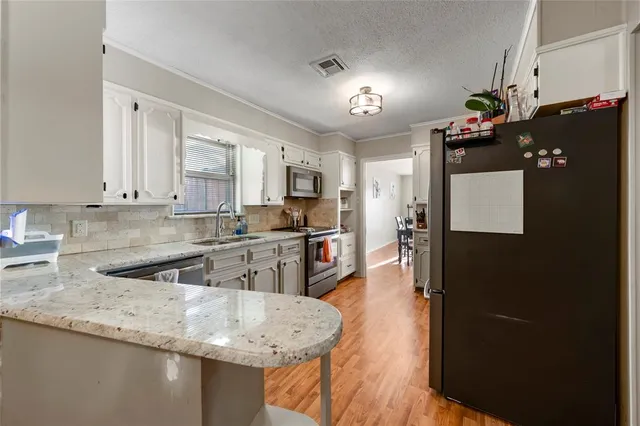 a kitchen with granite countertop white cabinets and refrigerator