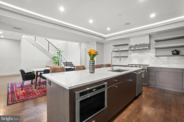 a large kitchen with stainless steel appliances a stove a chimney a sink and a refrigerator