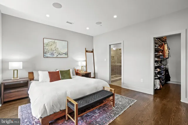 a spacious bedroom with a bed a dresser and wooden floor