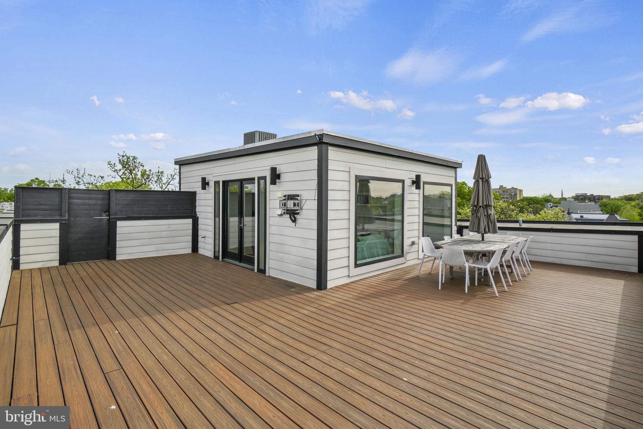 1201 Kenyon Street Northwest, Unit 5 Washington, DC 20010 - Photo 34 of 35 a view of a roof deck with table and chairs a barbeque with wooden floor and fence