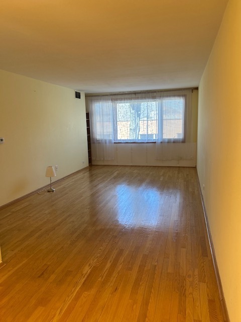 5915 West Gunnison Street, Unit 2F Chicago, IL 60630 - Photo 5 of 10 an empty room with wooden floor and windows