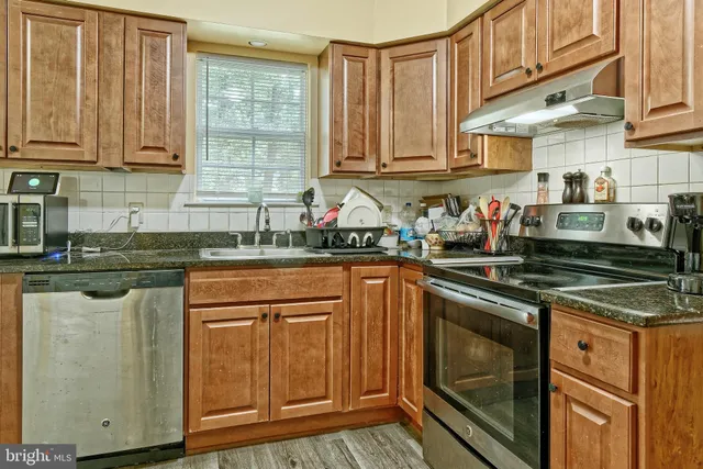 a kitchen with stainless steel appliances granite countertop a sink stove and cabinets