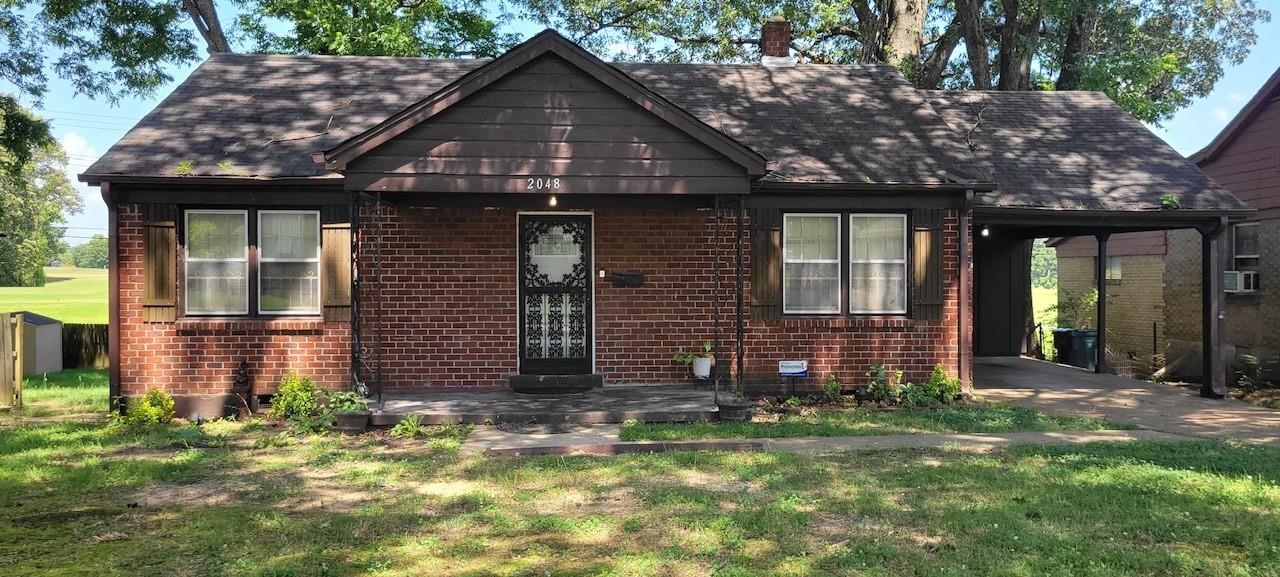 View of front of property with covered porch, a front lawn, brick siding, and a shingled roof