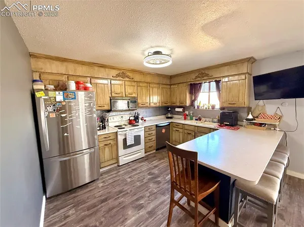 a kitchen with stainless steel appliances a refrigerator a stove a sink dishwasher a dining table and chairs with wooden floor