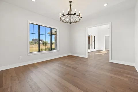 a large kitchen with stainless steel appliances kitchen island granite countertop a stove a sink a refrigerator and white cabinets with wooden floor