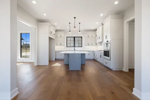 a kitchen with a sink chandelier and wooden floor