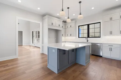 a kitchen with stainless steel appliances sink a stove and white cabinets