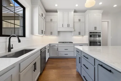 a kitchen with stainless steel appliances granite countertop a sink stove and a large refrigerator