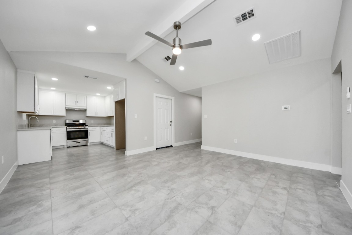 an empty room with stainless steel appliances kitchen island hardwood floor and a sink