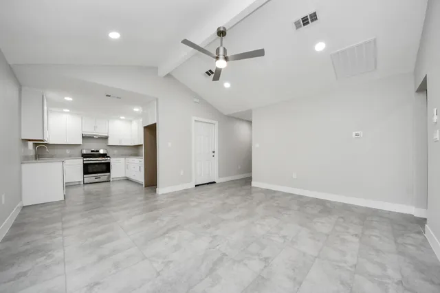 an empty room with stainless steel appliances kitchen island hardwood floor and a sink