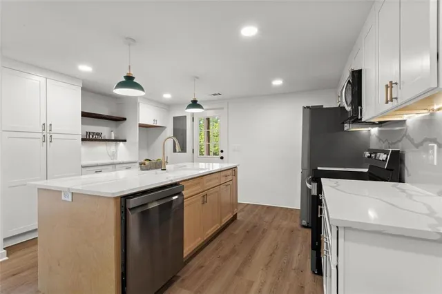 a kitchen with a sink a center island stainless steel appliances and cabinets