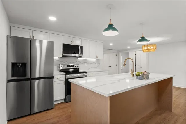 a kitchen with stainless steel appliances granite countertop a refrigerator a sink and a stove