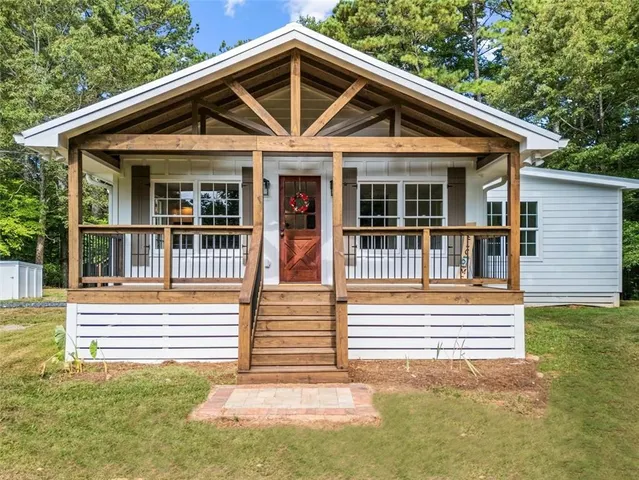 a view of a house with a small deck and a large tree front of house