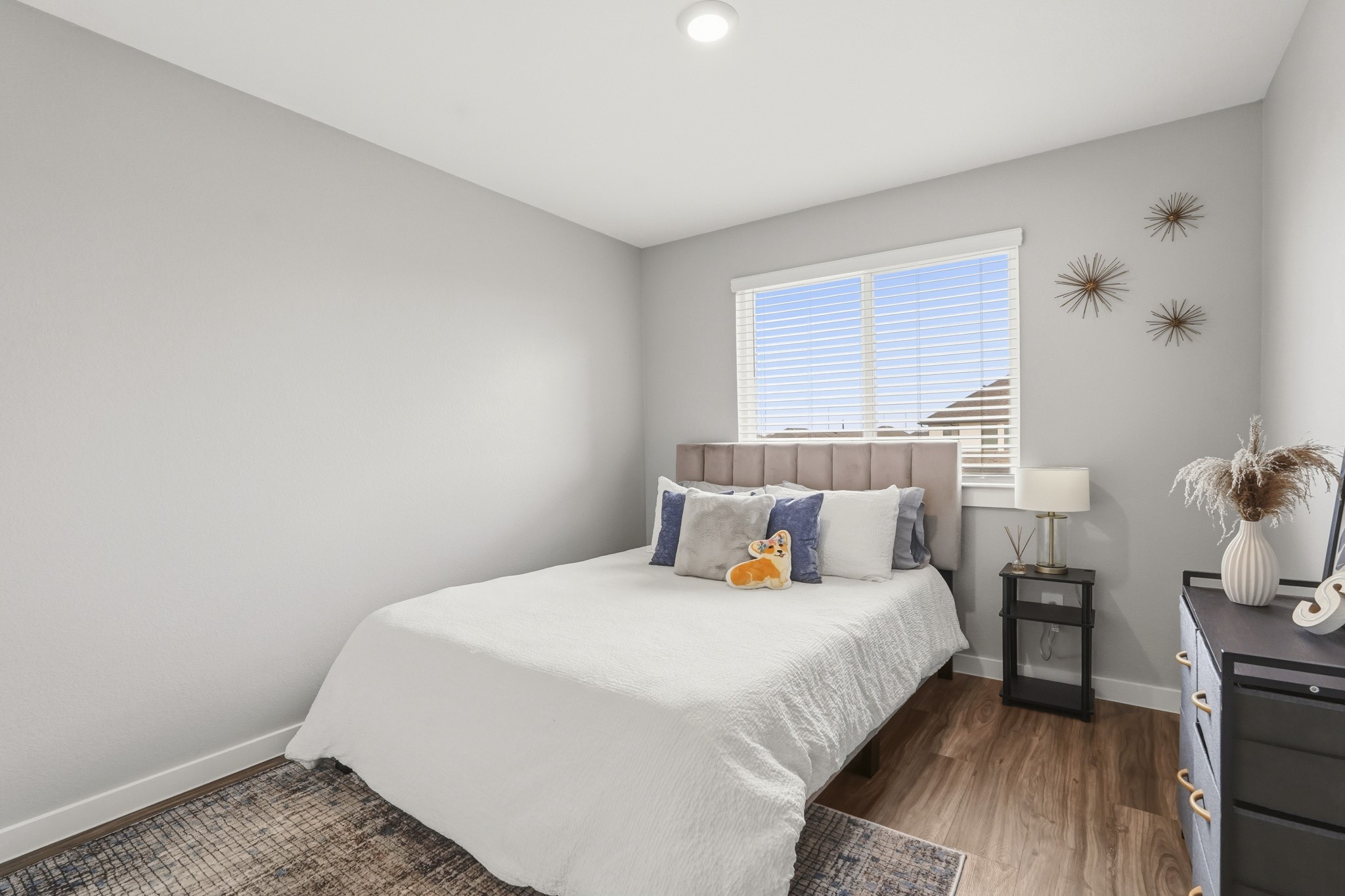22522 Modica Rift Lane Katy, TX 77449 - Photo 27 of 38 Charming, clean, and full of possibility, this well-proportioned secondary bedroom is ready to welcome whoever calls it home. Neutral grey walls and warm hardwood-style floors create a versatile canvas, while a sunny window, upholstered headboard, and sweet gold starburst wall décor bring warmth and character. A great guest room, kids' room, or cozy retreat — this space checks every box with ease and style.