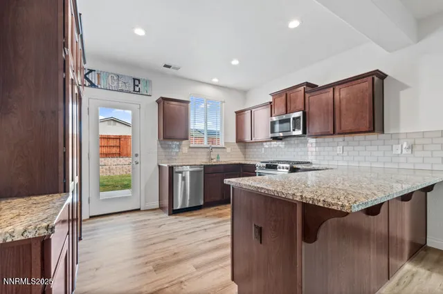 a kitchen with stainless steel appliances granite countertop wooden cabinets a stove top oven a sink and dishwasher
