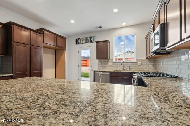 a kitchen with granite countertop a sink stainless steel appliances and cabinets