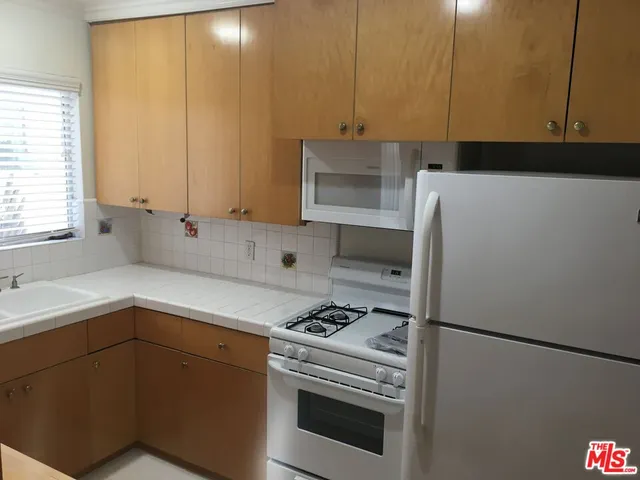 a kitchen with a refrigerator sink and cabinets