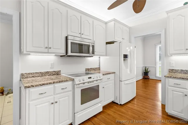 a kitchen with stainless steel appliances granite countertop a stove a microwave and a white cabinets