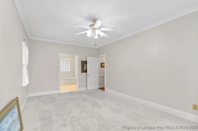 a view of an empty room with chandelier fan and windows