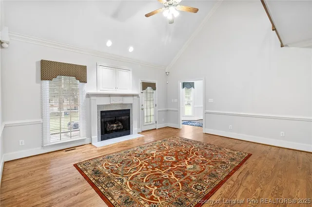 an empty room with wooden floor fireplace and windows