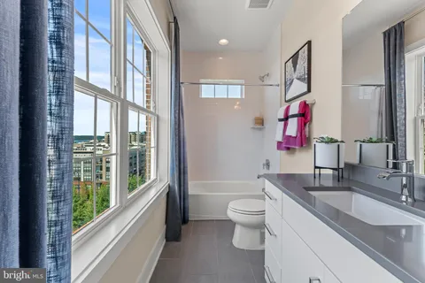 a bathroom with a granite countertop sink a toilet and a large mirror next to a window