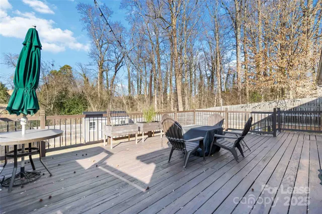a view of a roof deck with table and chairs couches with wooden floor and fence