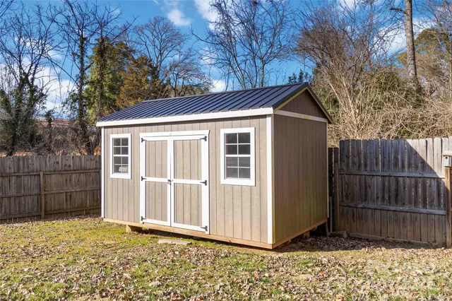 a view of a house with a large window and wooden fence