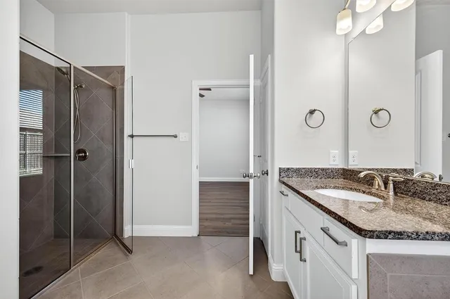 a bathroom with a granite countertop shower sink and mirror
