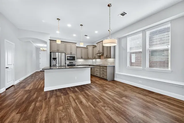 a large kitchen with kitchen island a stove a refrigerator a sink and a oven with large windows