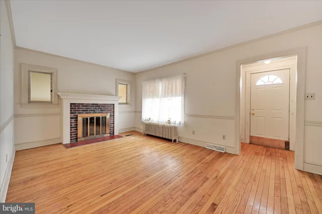 an empty room with wooden floor fireplace and windows