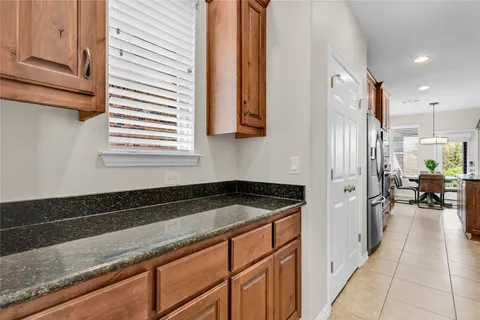 a utility room with stainless steel appliances granite countertop a sink and a refrigerator