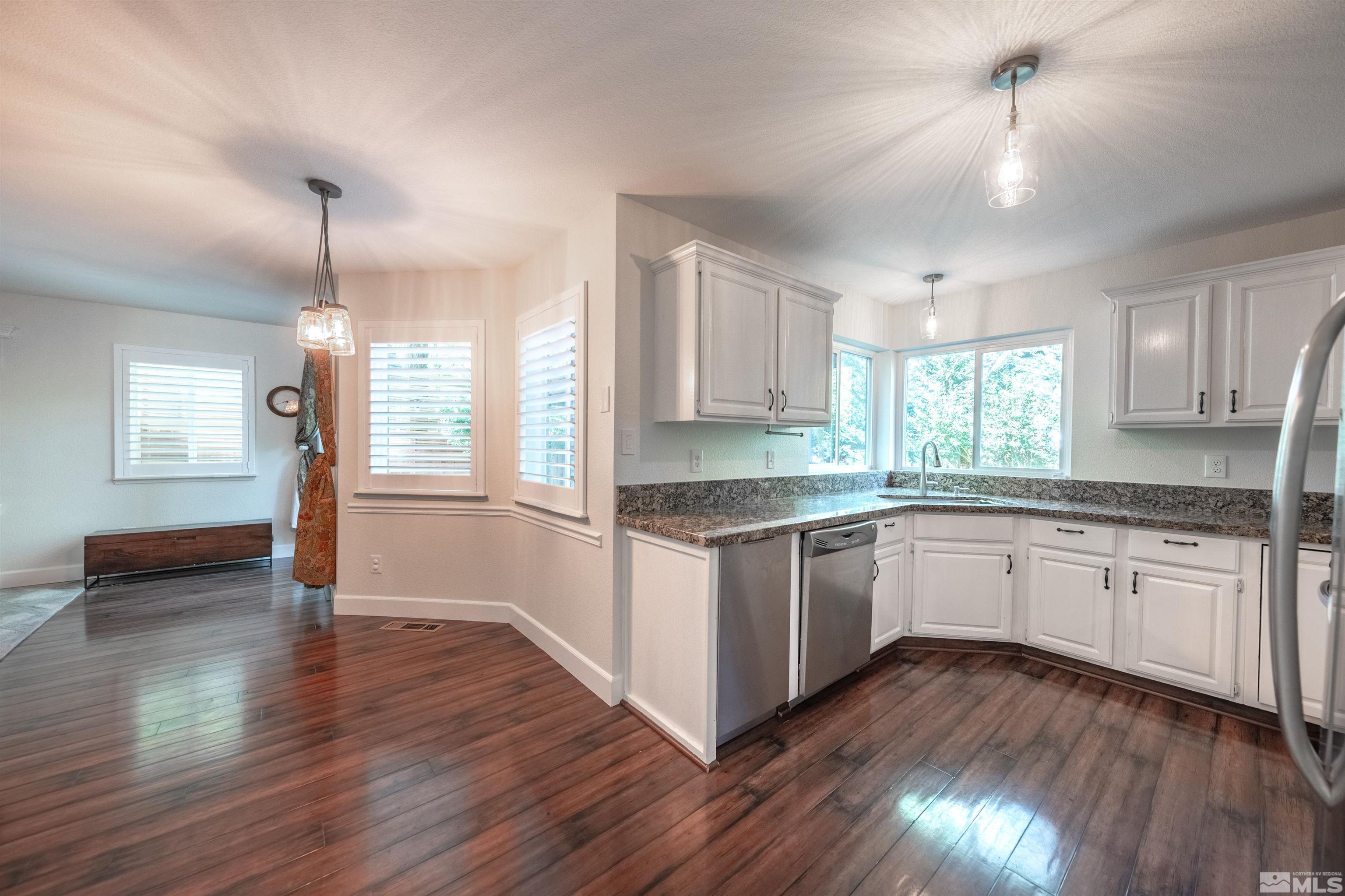 110 Riverhaven Place Reno, NV 89519 - Photo 11 of 40 a kitchen with granite countertop wooden floors and white cabinets