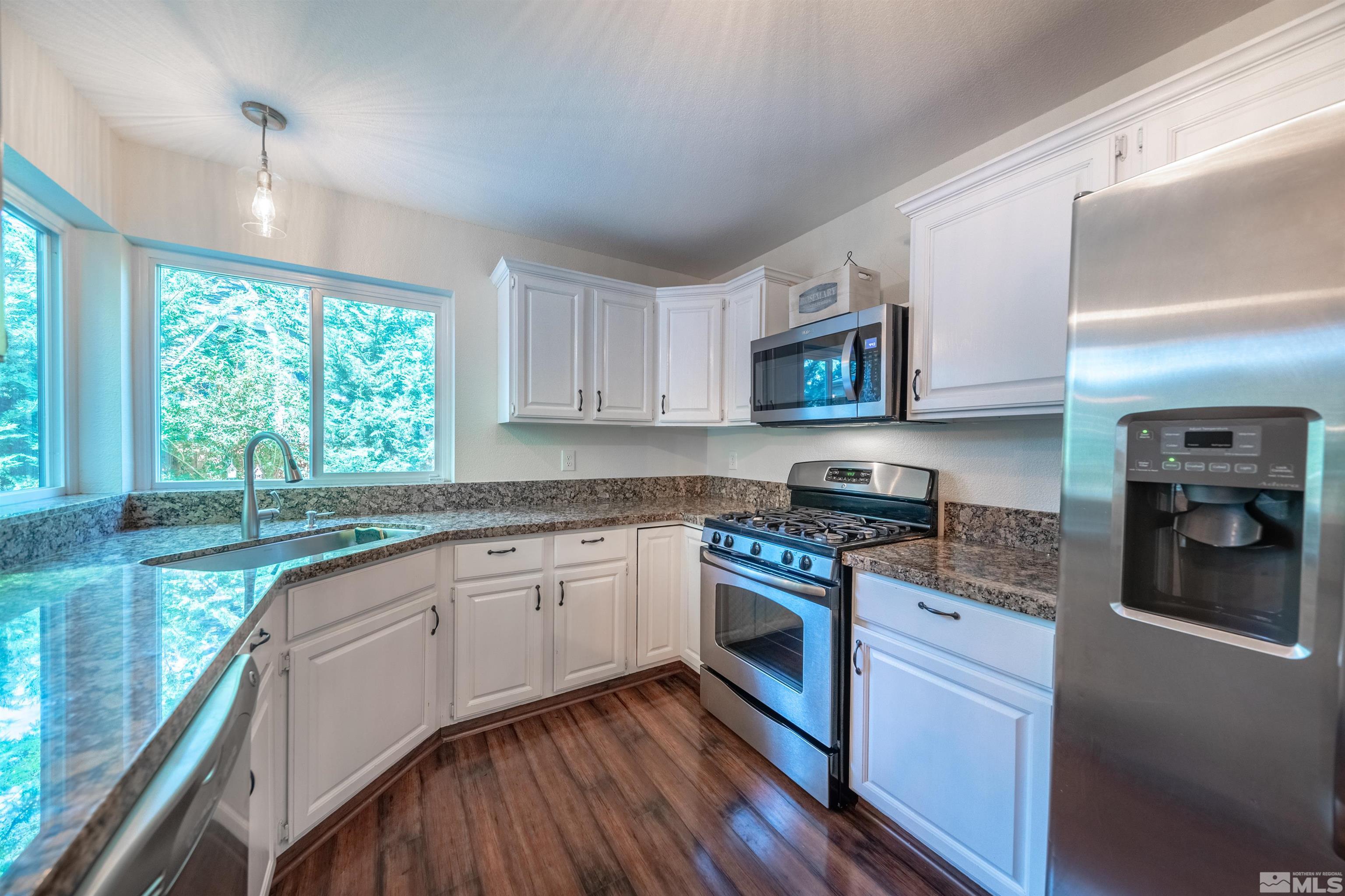 110 Riverhaven Place Reno, NV 89519 - Photo 14 of 40 a kitchen with stainless steel appliances granite countertop wooden cabinets a stove a sink and a large window