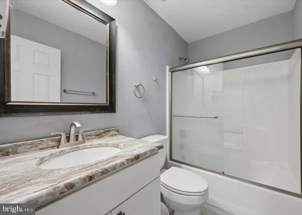 a bathroom with a granite countertop sink toilet and shower