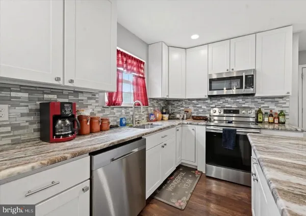 a kitchen with stainless steel appliances granite countertop a stove sink and cabinets