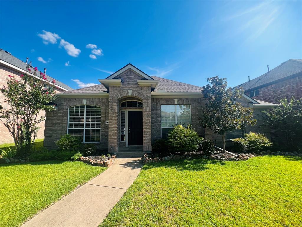 View of front facade with a shingled roof, a front yard, and brick siding