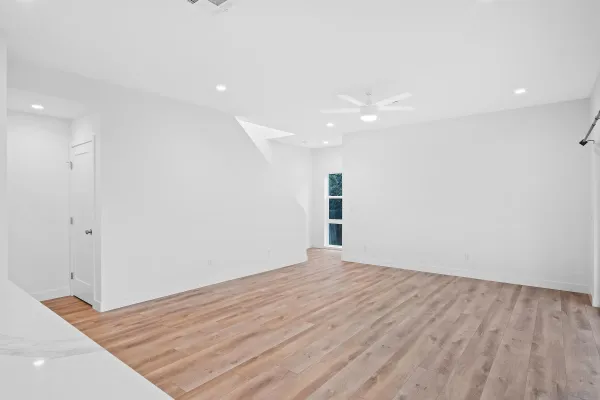 a view of an empty room with wooden floor and a window